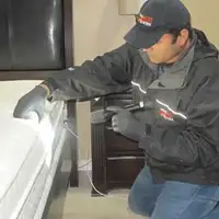 Bed bug inspection technician checking a mattress and bed frame for signs of infestation in Buffalo, NY