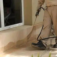 General pest control technician spraying exterior perimeter around a home in Buffalo, NY