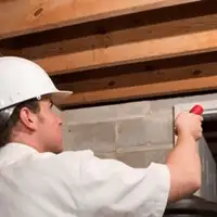 Termite inspection technician checking a basement wall and framing for termite activity in Buffalo, NY